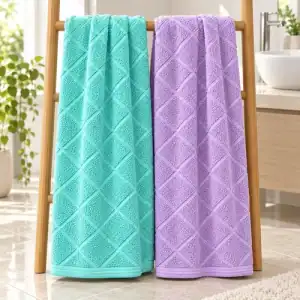 Full-size aqua and orchid bamboo bath towels with an angled woven cross design hanging in a bathroom