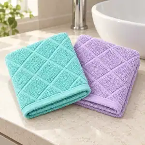 Folded aqua and orchid face washers with an angled woven cross design beside a bathroom basin